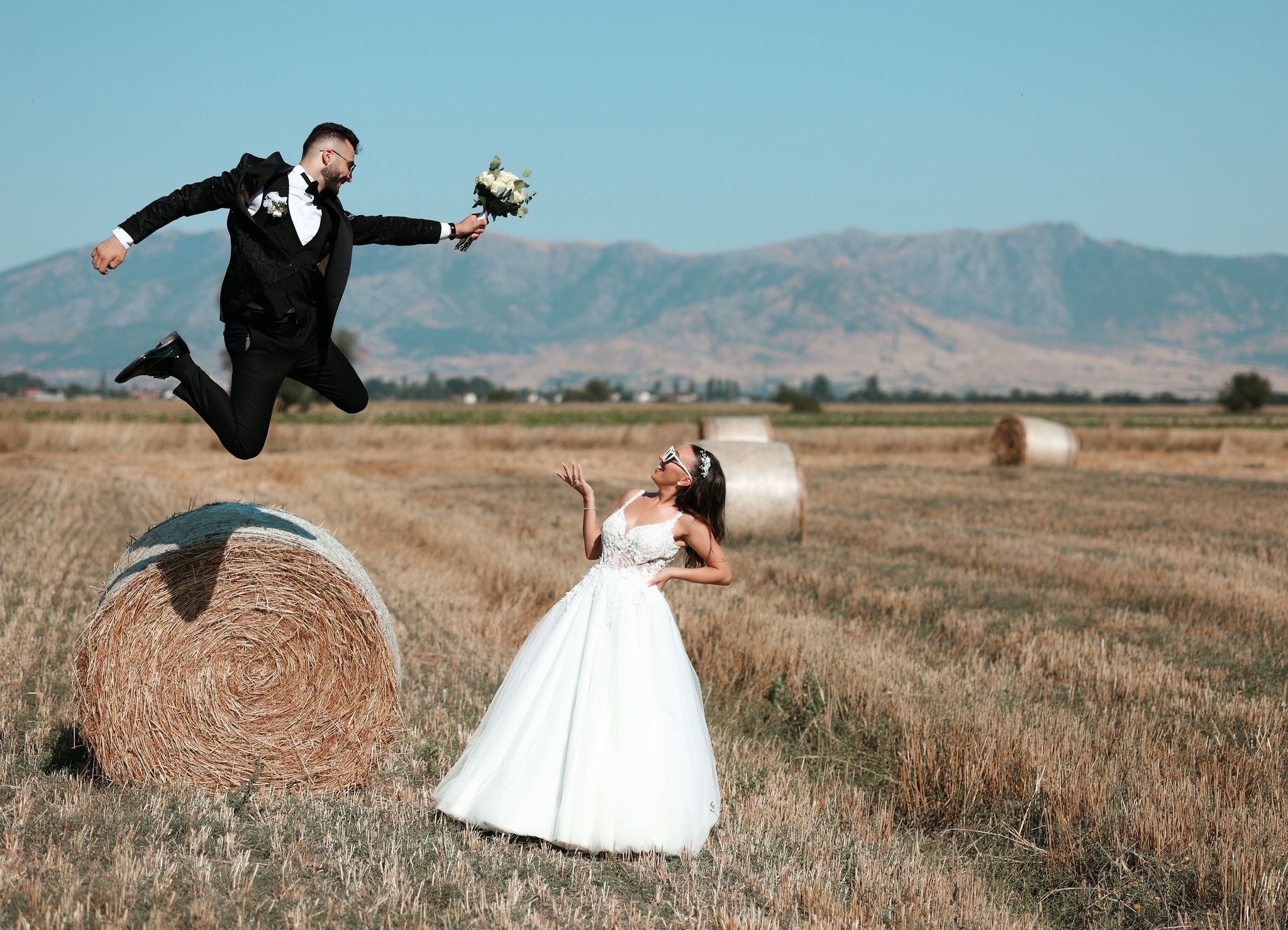 Младоженец скока од пласт слама во поле
